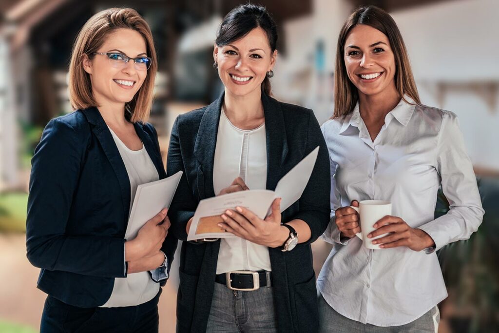 Three woman executive assistants standing looking at document